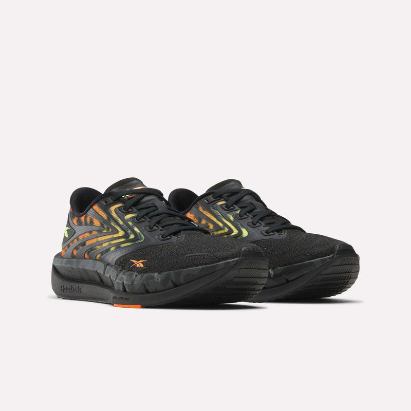 Reebok Women's FloatZig Tread Running Shoes feature a breathable mesh upper, gradient yellow and orange wave patterns on the sides, black soles, and Reebok logo accents, shown against a white background.