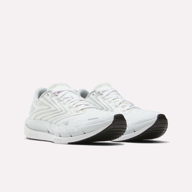 A pair of Reebok Women's FloatZig Tread Running Shoes in white with light gray accents, breathable mesh uppers, and black rubber outsoles are displayed side by side on a plain white background.
