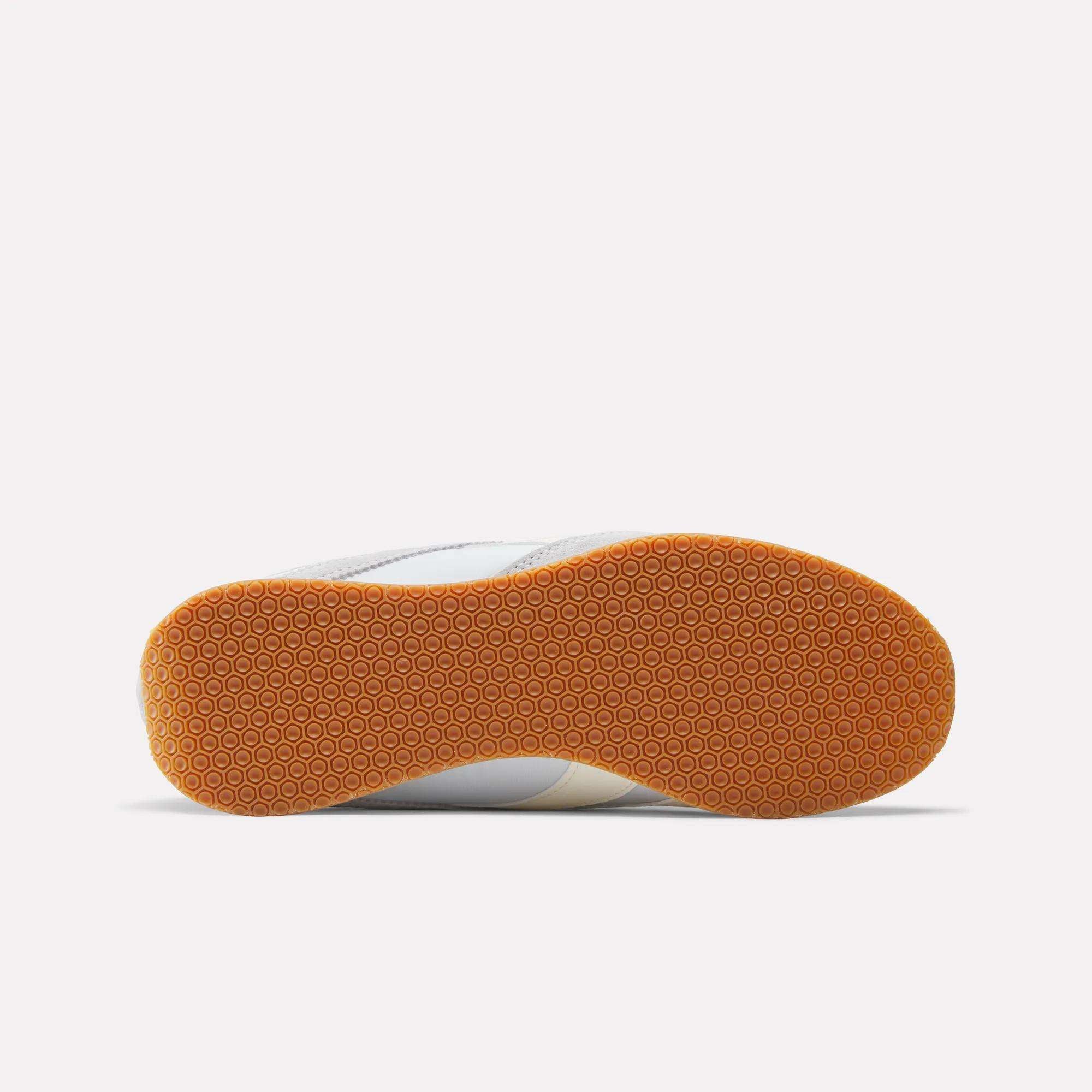 The image displays the sole of Reebok R400 Shoes with a light brown hexagonal pattern. The rest of the mainly white retro sneaker is partially visible against a plain white background.