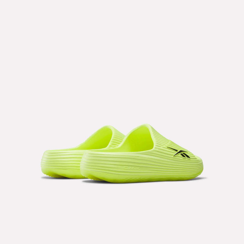 A pair of neon yellow Reebok DMX Recovery Walking Slides featuring ribbed textured soles, a black Reebok logo on one upper, and moving air cushioning for comfort. Shown against a plain white background.
