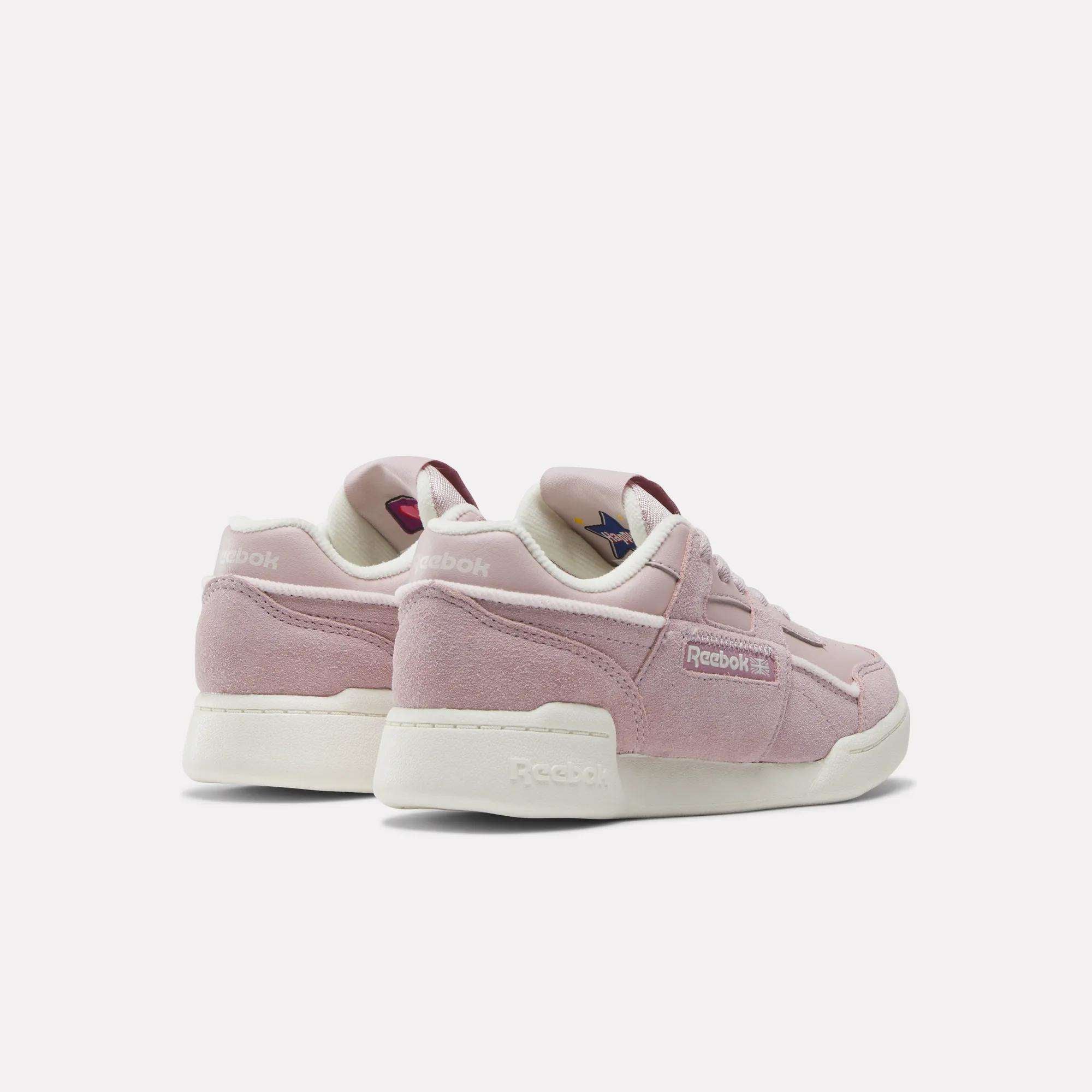 A pair of pink Reebok Workout Plus Shoes for little kids, with white soles and suede material, are shown from the back and side on a light background. The sporty shoes display Reebok branding on the sides and heels.