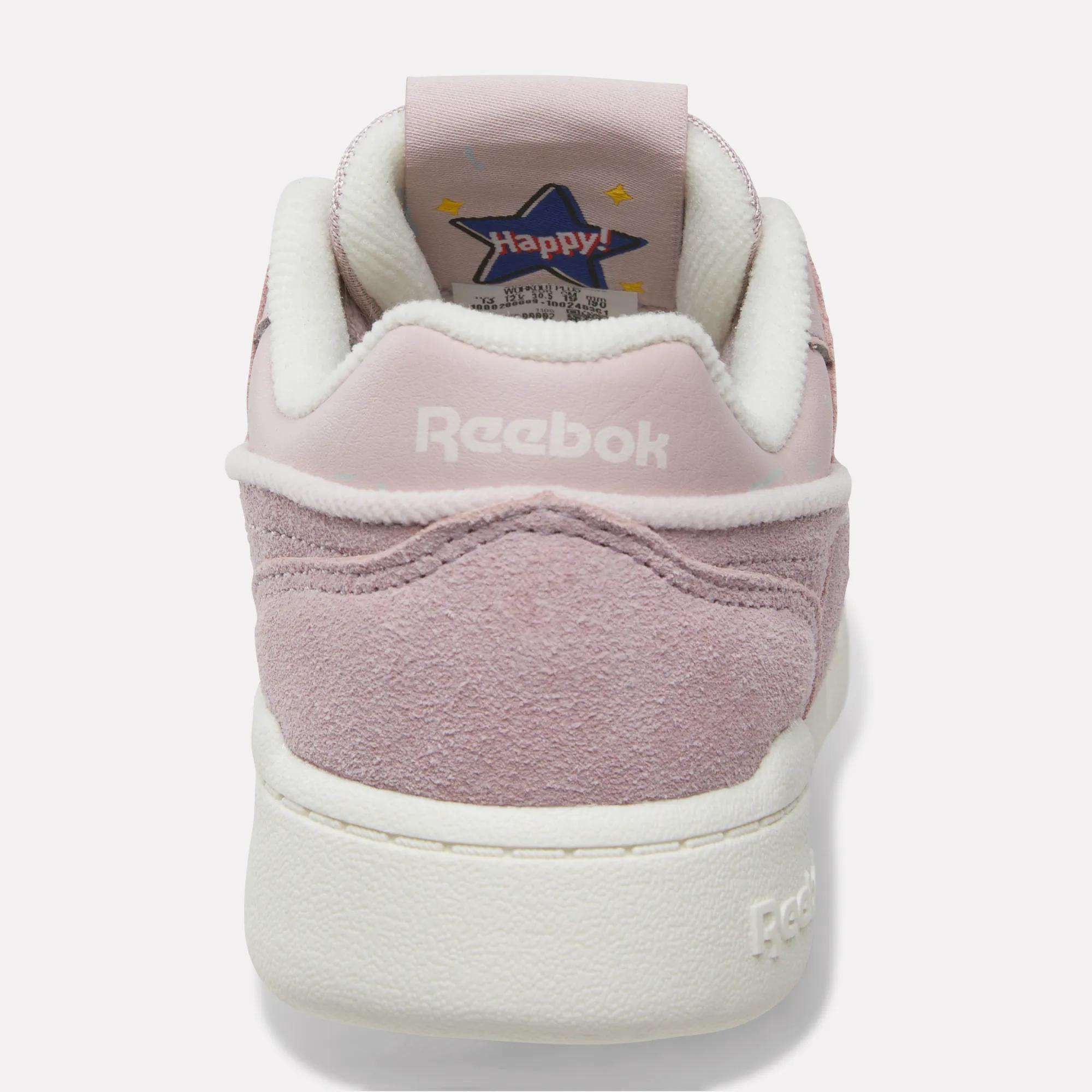 A pink suede Reebok Workout Plus Shoe for little kids, shown from the back with “Reebok” stitched in white on the heel and a star-shaped “Happy!” graphic on the inner tongue—sporty and perfect for any fun outing.