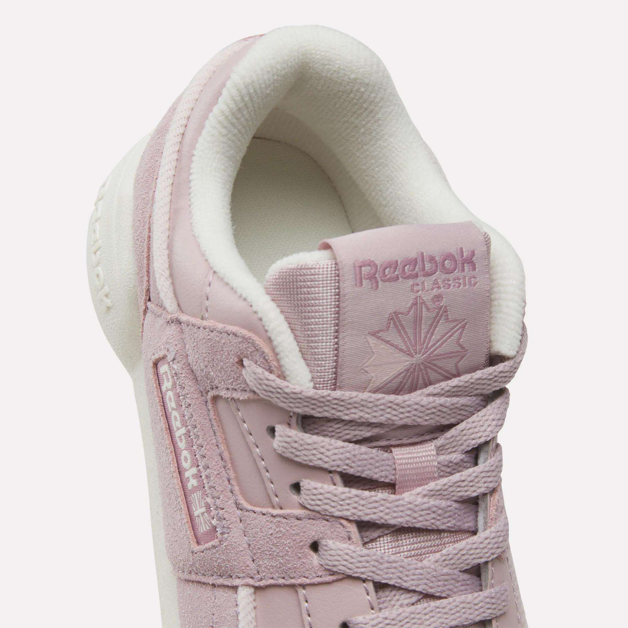 Close-up of Reebok Workout Plus Shoes for little kids in light pink, featuring white lining, laces, and visible Reebok logos on the tongue and side—perfect sporty footwear for everyday style.