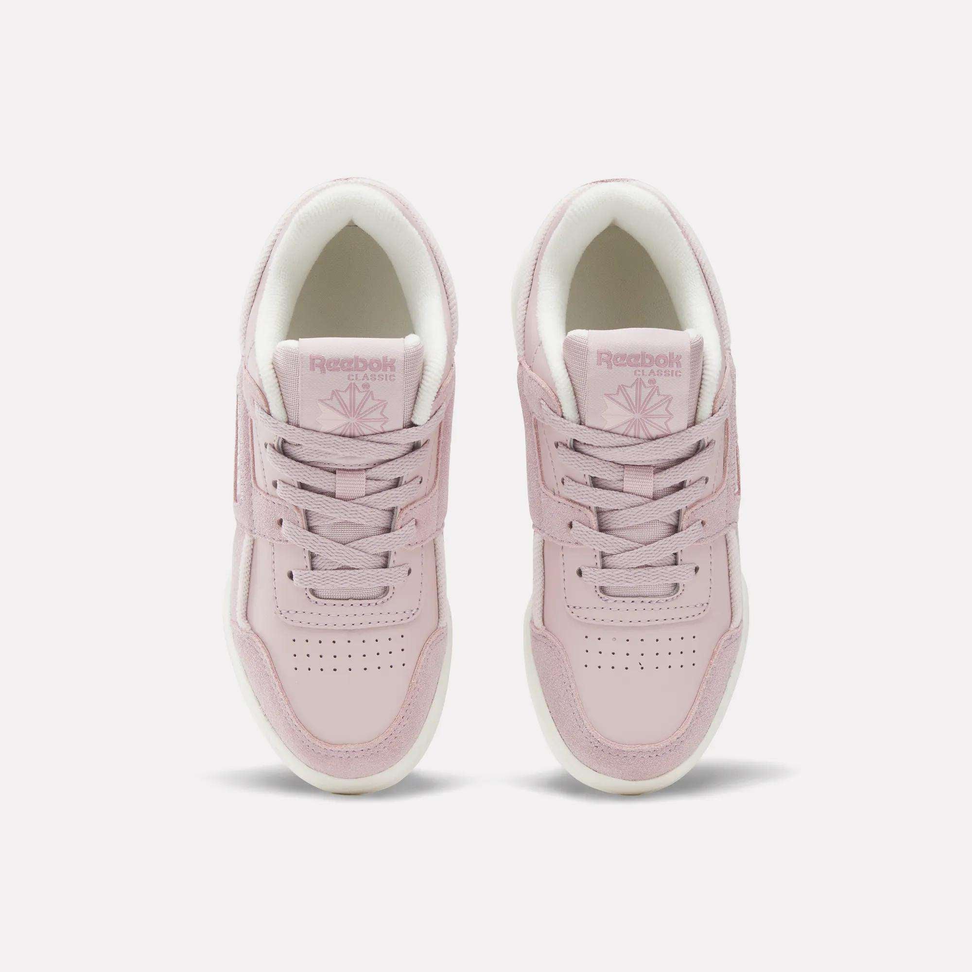 A pair of light pink Reebok Workout Plus Shoes for little kids, featuring white soles and laces, is displayed from above on a plain white background.