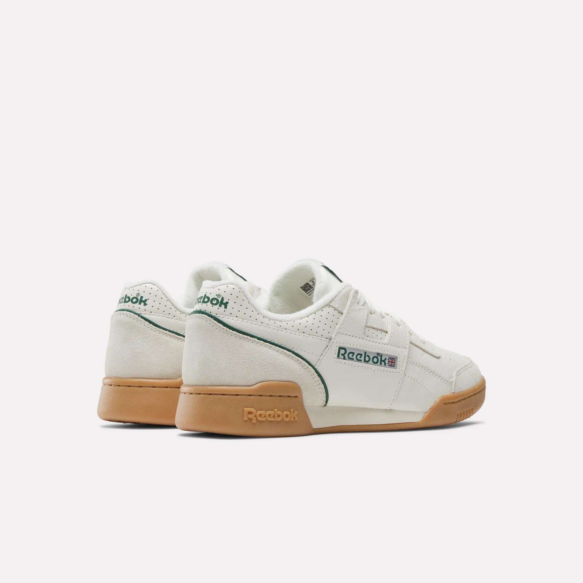 A pair of Reebok Workout Plus Shoes in white with green accents and gum soles, displayed on a plain white background. The sneakers are angled to show the heels and sides, echoing classic ’80s fitness style.
