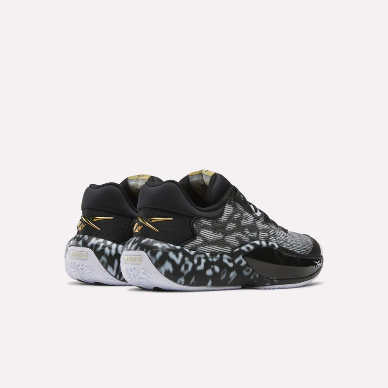 Reebok Engine A 26 Basketball Shoes in black and white feature a spotted pattern, gold accents, white soles with ERS+ cushioning, and are displayed from the rear and side on a plain light background.