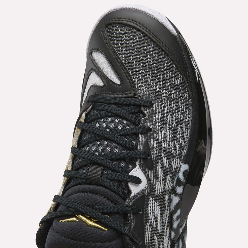 Close-up of Reebok Engine A 26 Basketball Shoes in black, showcasing a mesh-patterned upper, black laces, glossy side accents, energy return cushioning, and a gold logo on the tongue for lightweight support.