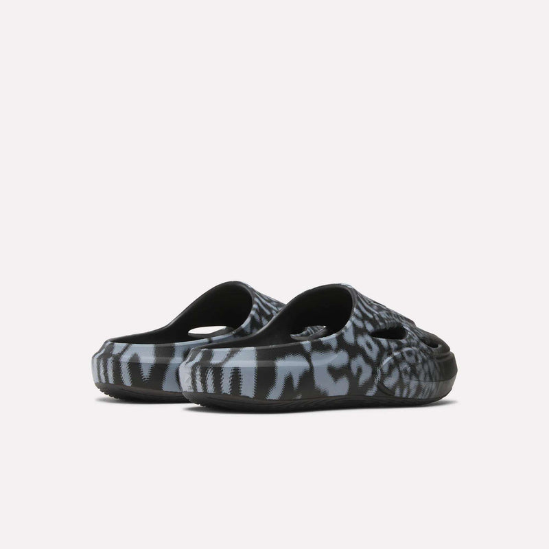 A pair of Reebok DMX Recovery Mules in black and grey with a bold animal print and DMX cushioning, shown from the back on a plain white background.