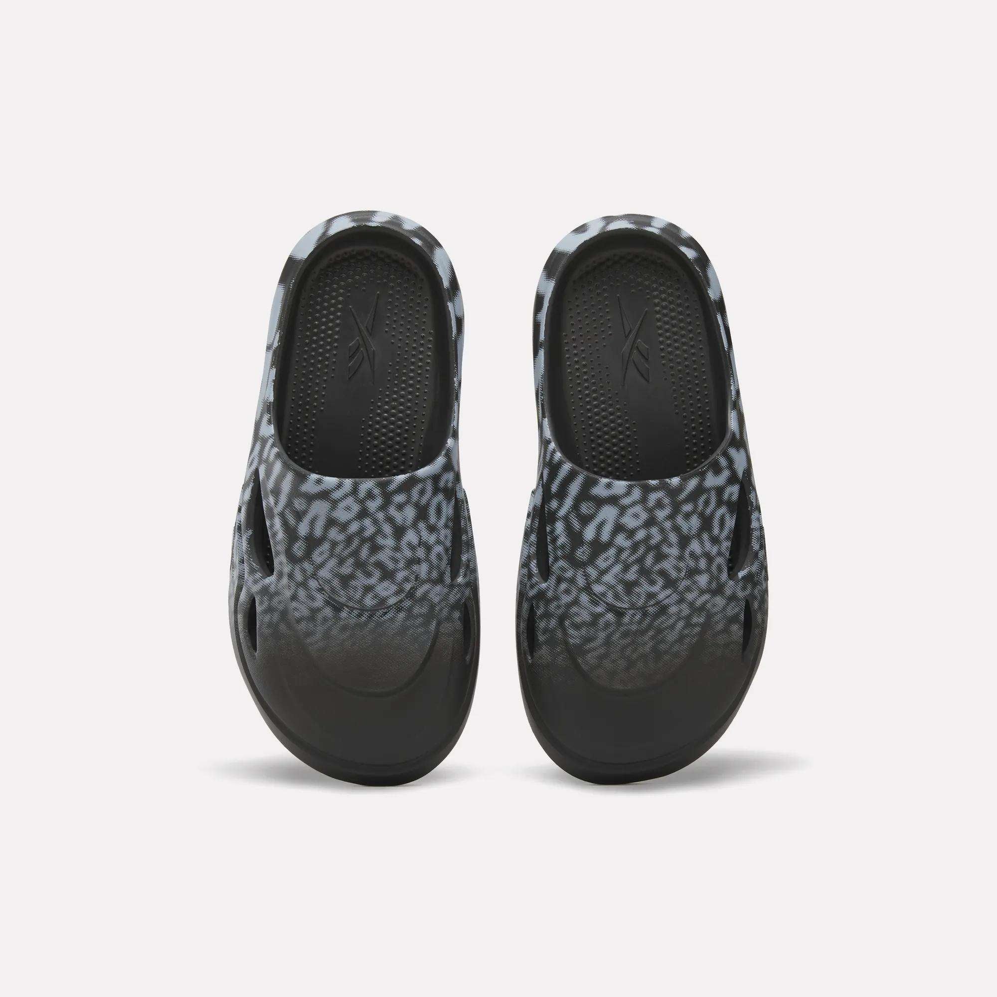 The Reebok DMX Recovery Mules feature a black and gray leopard print, shown from above on a white background—ideal recovery footwear after long days.