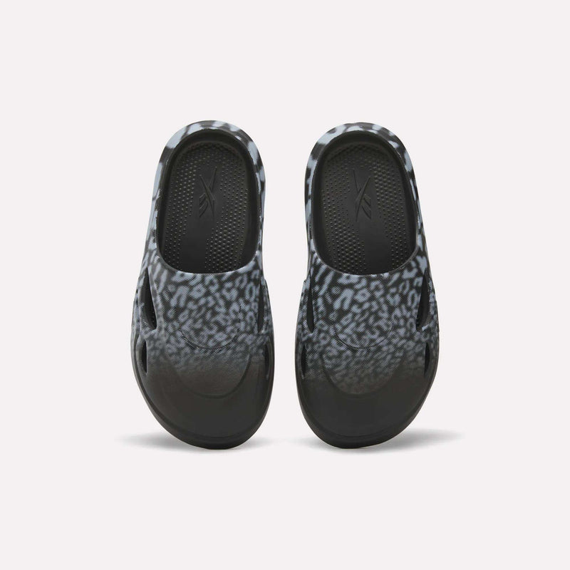 The Reebok DMX Recovery Mules feature a black and gray leopard print, shown from above on a white background—ideal recovery footwear after long days.