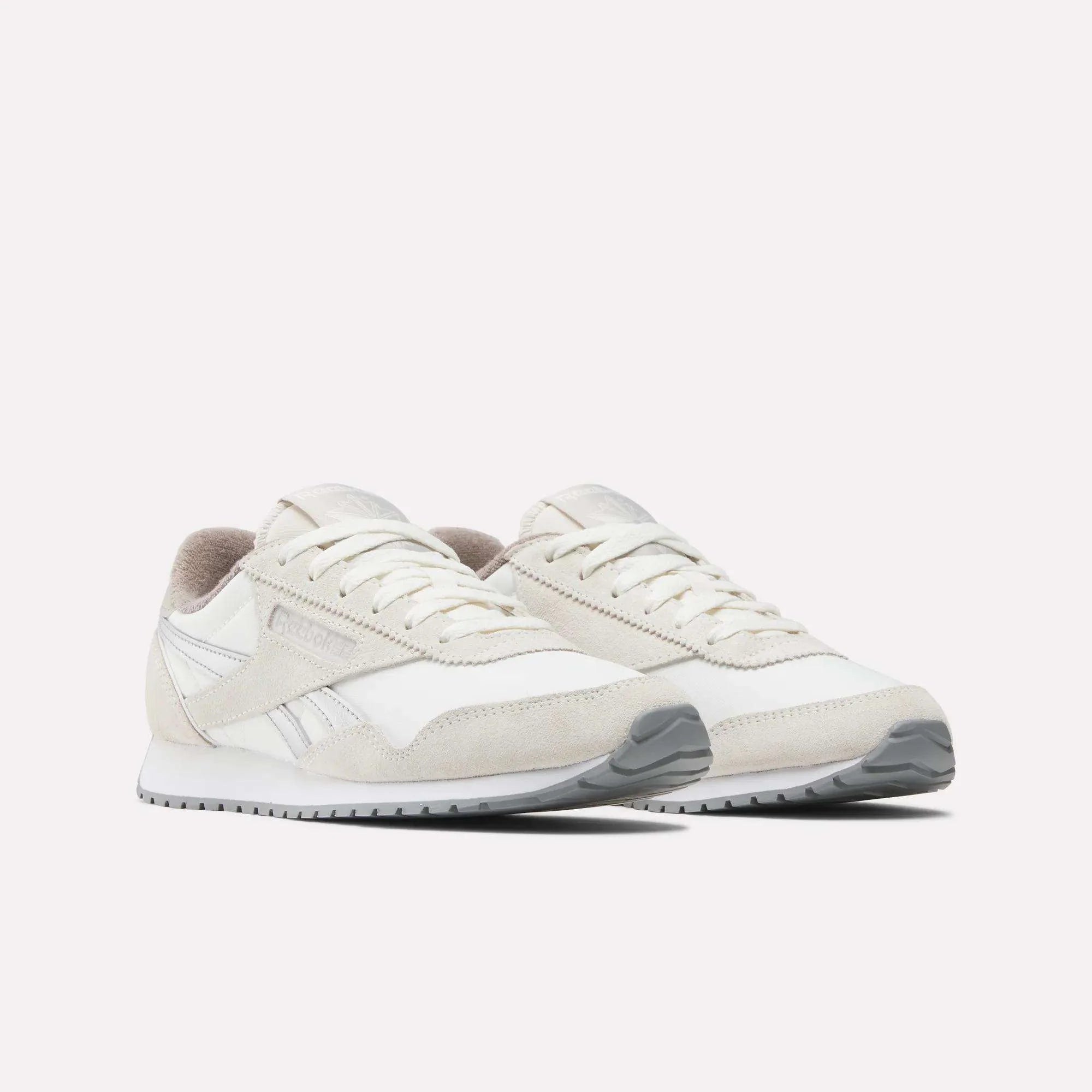 A pair of stylish white and light gray Reebok sneakers with suede and mesh details, shown on a plain white background.