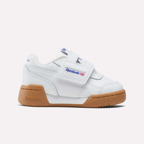 The Reebok Kids' Workout Plus Shoes for babies and toddlers feature a white design with gum sole, H-strap closure, blue Reebok logo, and a small Union Jack on the side, shown against a simple light background.