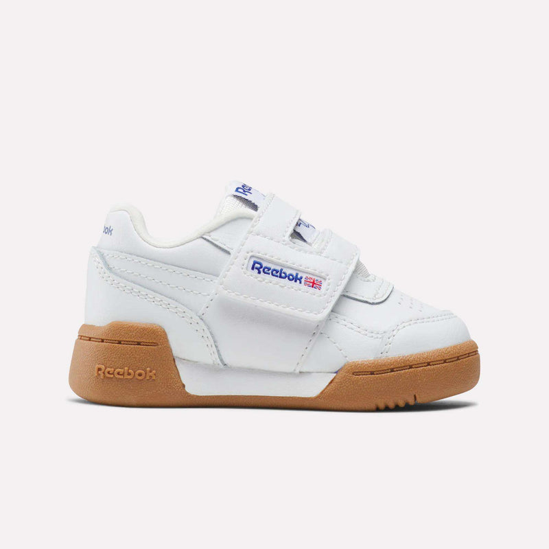 The Reebok Kids' Workout Plus Shoes for babies and toddlers feature a white design with gum sole, H-strap closure, blue Reebok logo, and a small Union Jack on the side, shown against a simple light background.