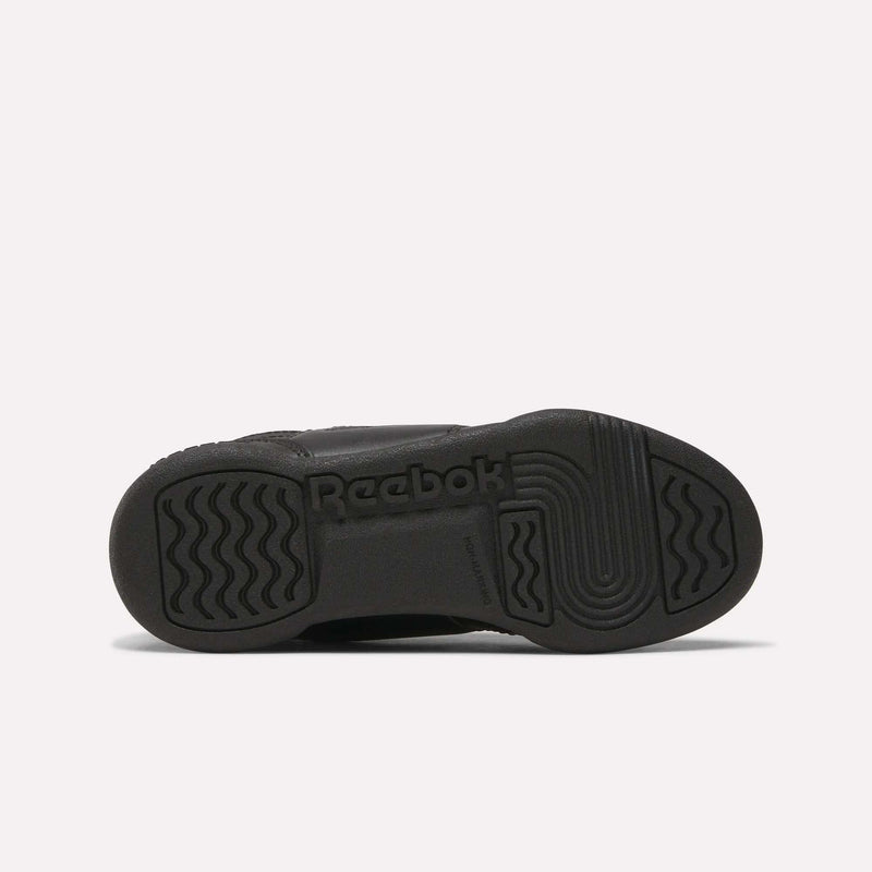 The image shows the black rubber sole of Reebok Workout Plus Shoes for little kids, viewed from the bottom, with wavy and straight tread patterns and the Reebok logo embossed in the center.