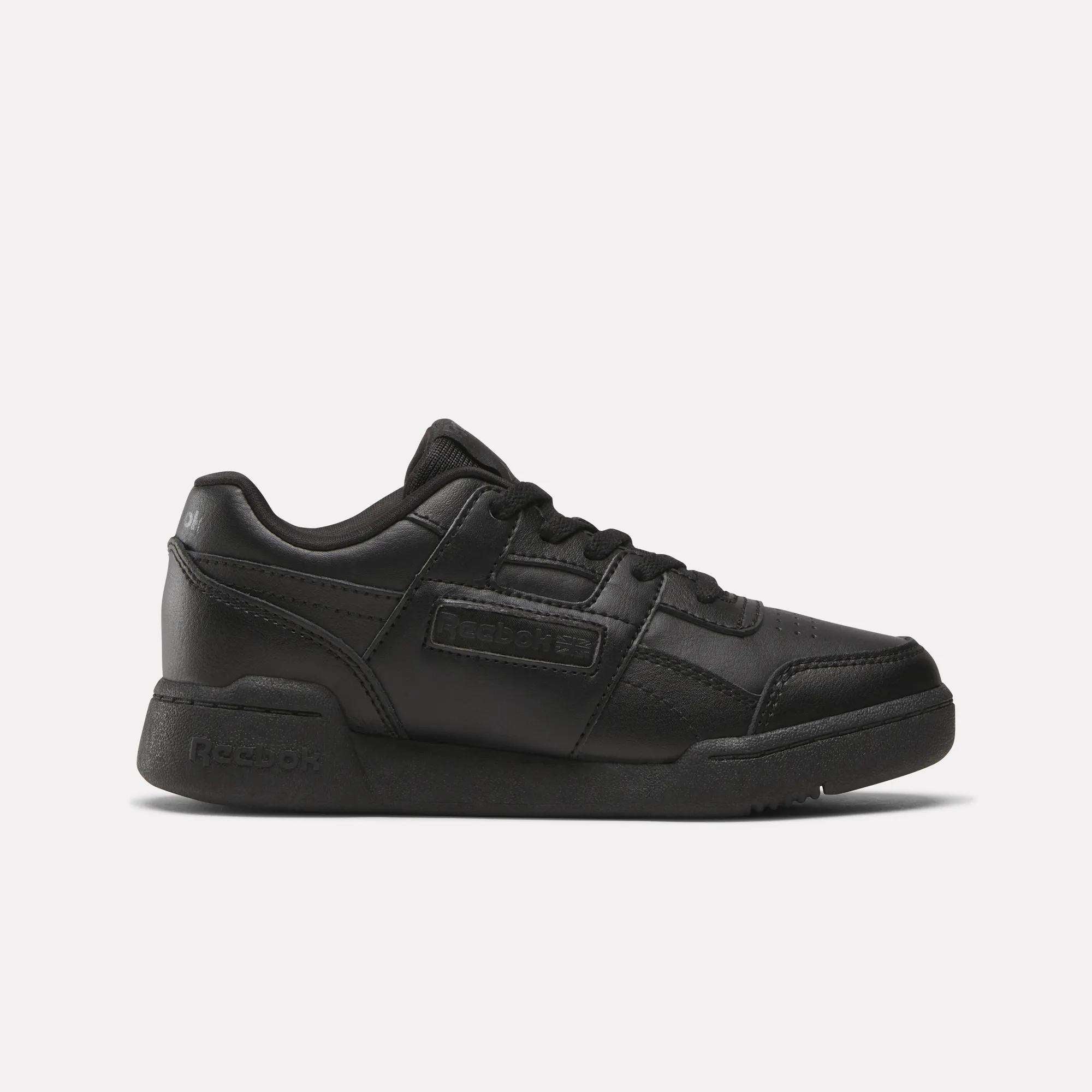 The Reebok Workout Plus Shoes for little kids feature a black low-top design, lace-up closure, and rubber sole, making them stylish and sporty. Displayed on a plain white background.