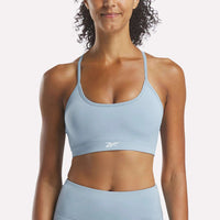Woman wearing a light blue sports bra and leggings with a visible brand logo on a white background