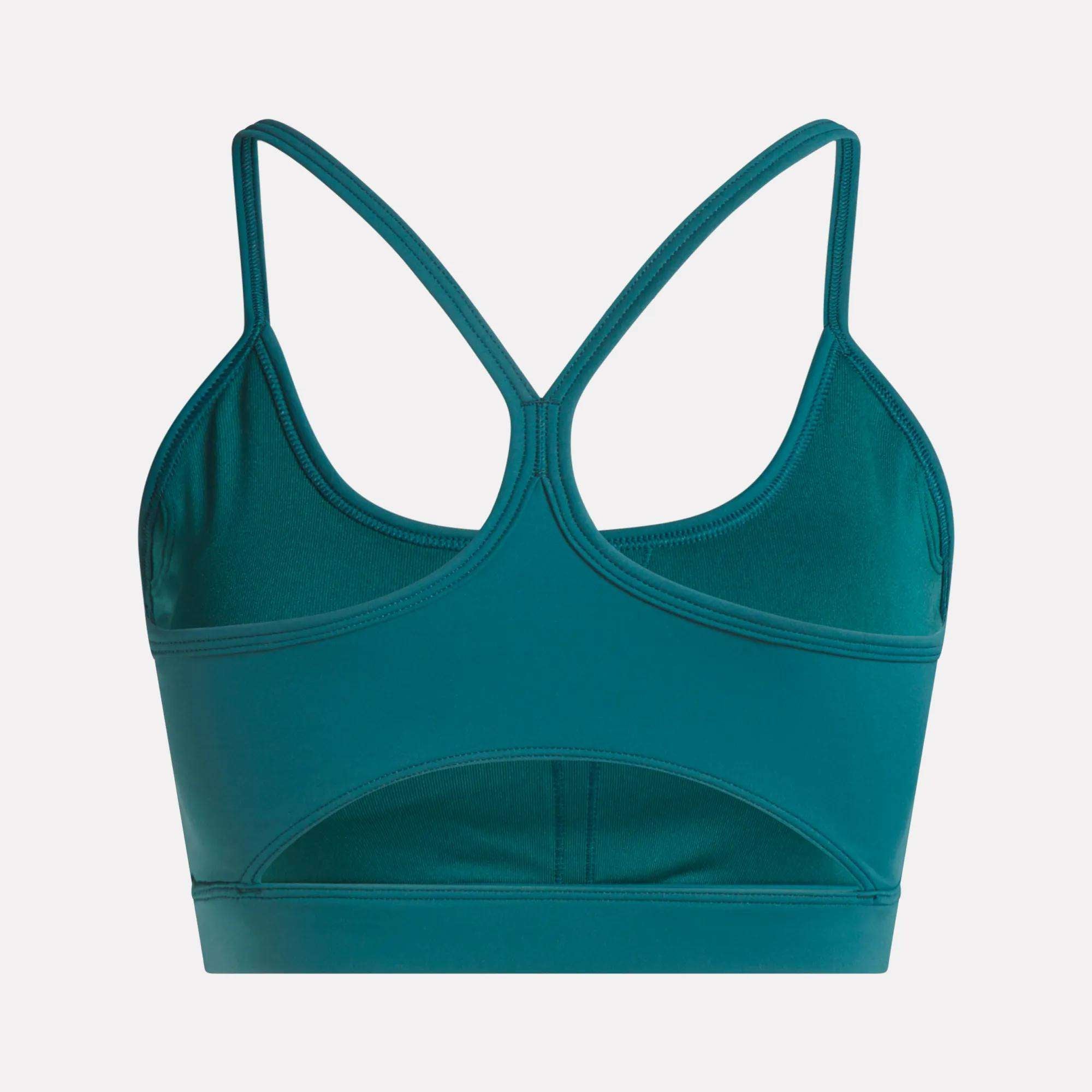 The Reebok Women's Core Strappy Bra - Medium Support in teal features thin racerback straps, a lower-back cutout, and quick-drying fabric—ideal for medium-impact workouts. Shown on a plain white background.