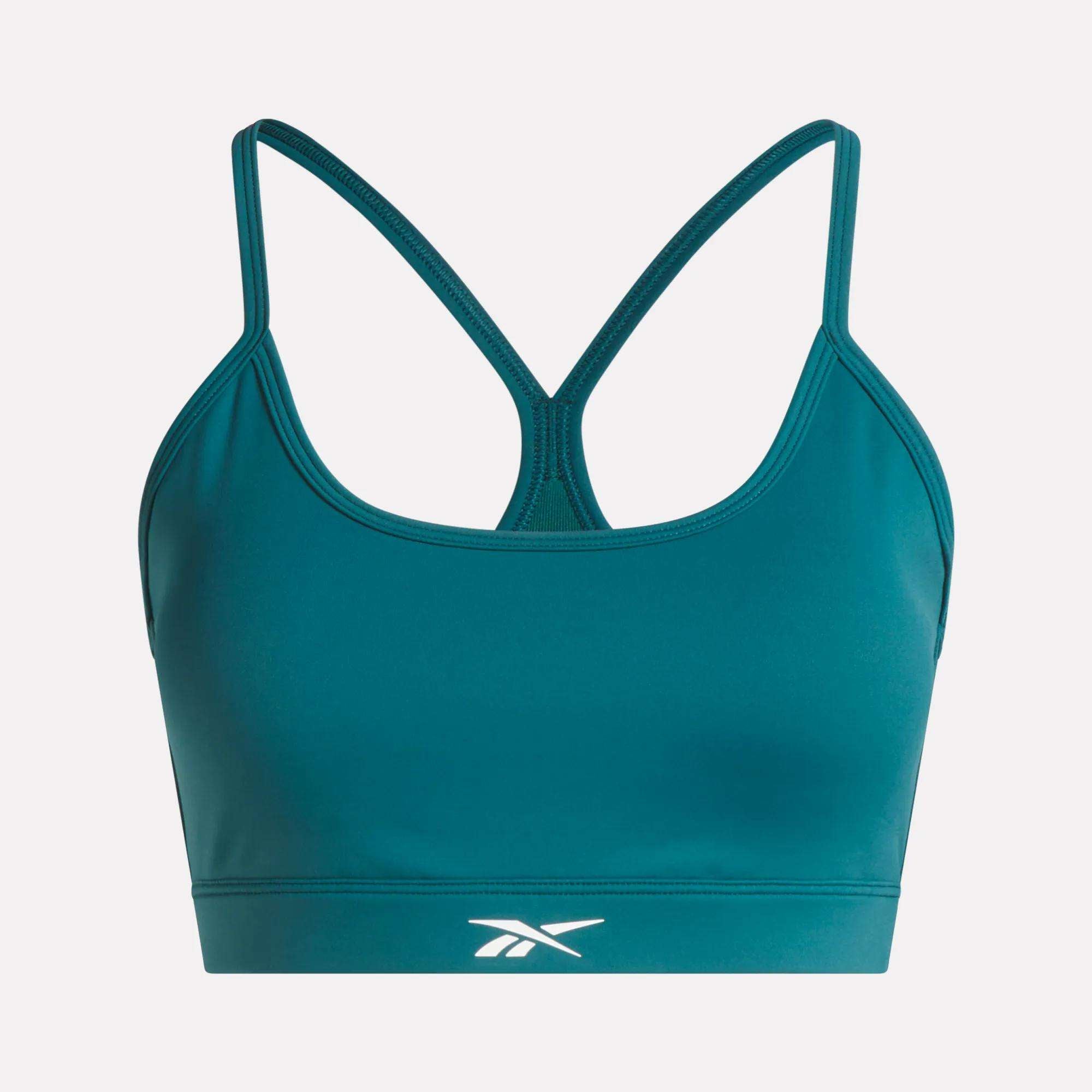 The Reebok Women's Core Strappy Bra - Medium Support in teal features thin racerback straps, quick-drying fabric, and a front white logo, perfect for medium-impact workouts. Displayed on a plain light background.