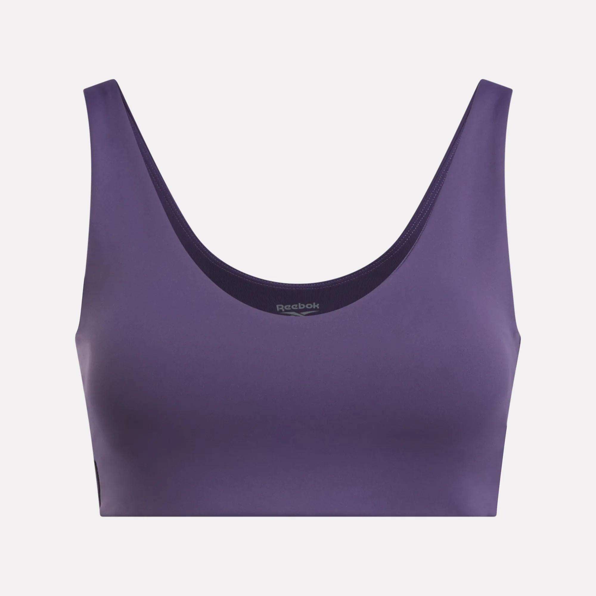 The Reebok Women's Yoga V-Neck Bra in purple features wide straps and a V-neck, providing medium-impact support for studio workouts. Shown against a plain light background.