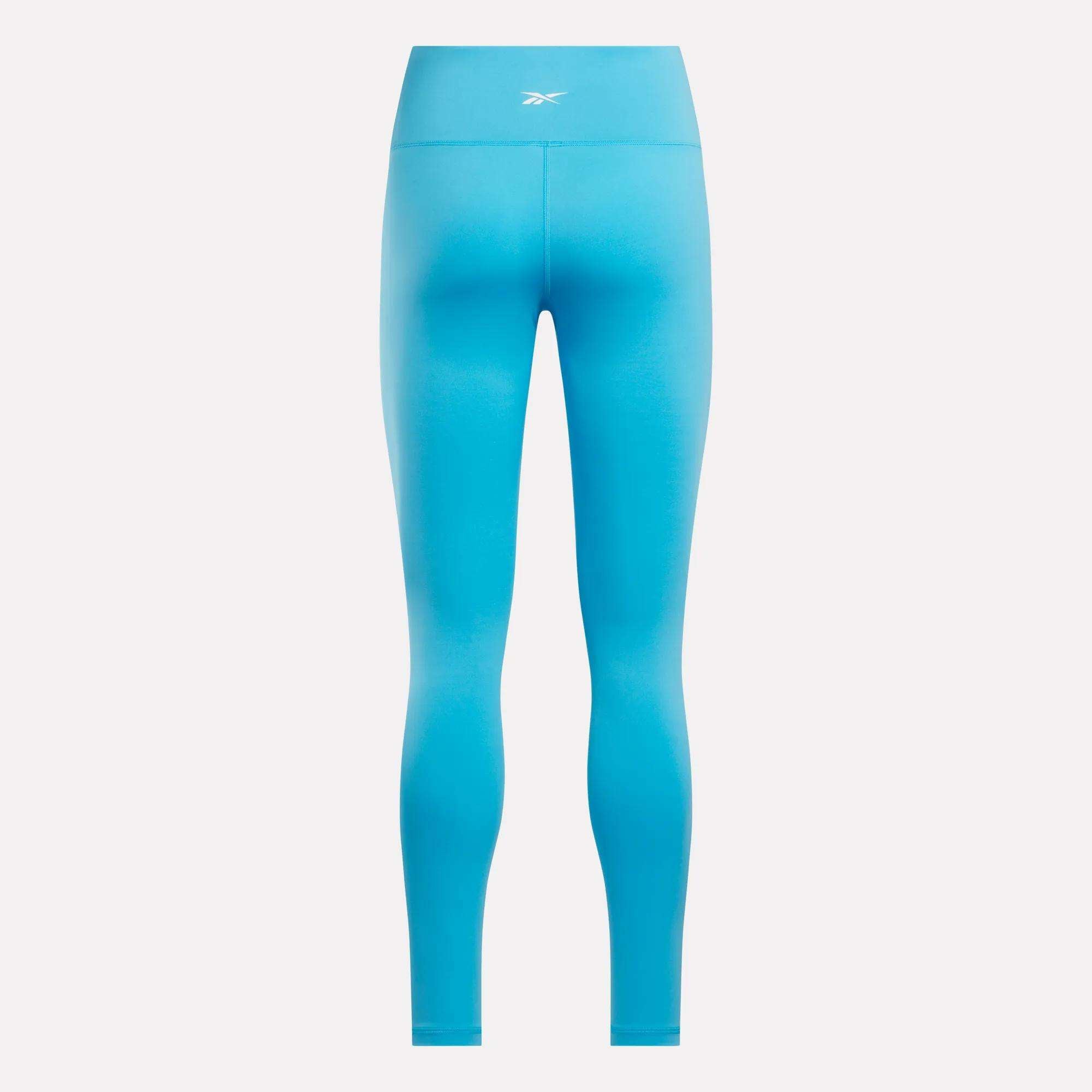 Women's Core High-Rise Leggings by Reebok in bright blue, shown from the back with a small white waistband logo and seamless RBK-DRY fabric—ideal for cycling or daily wear—set against a plain light background.