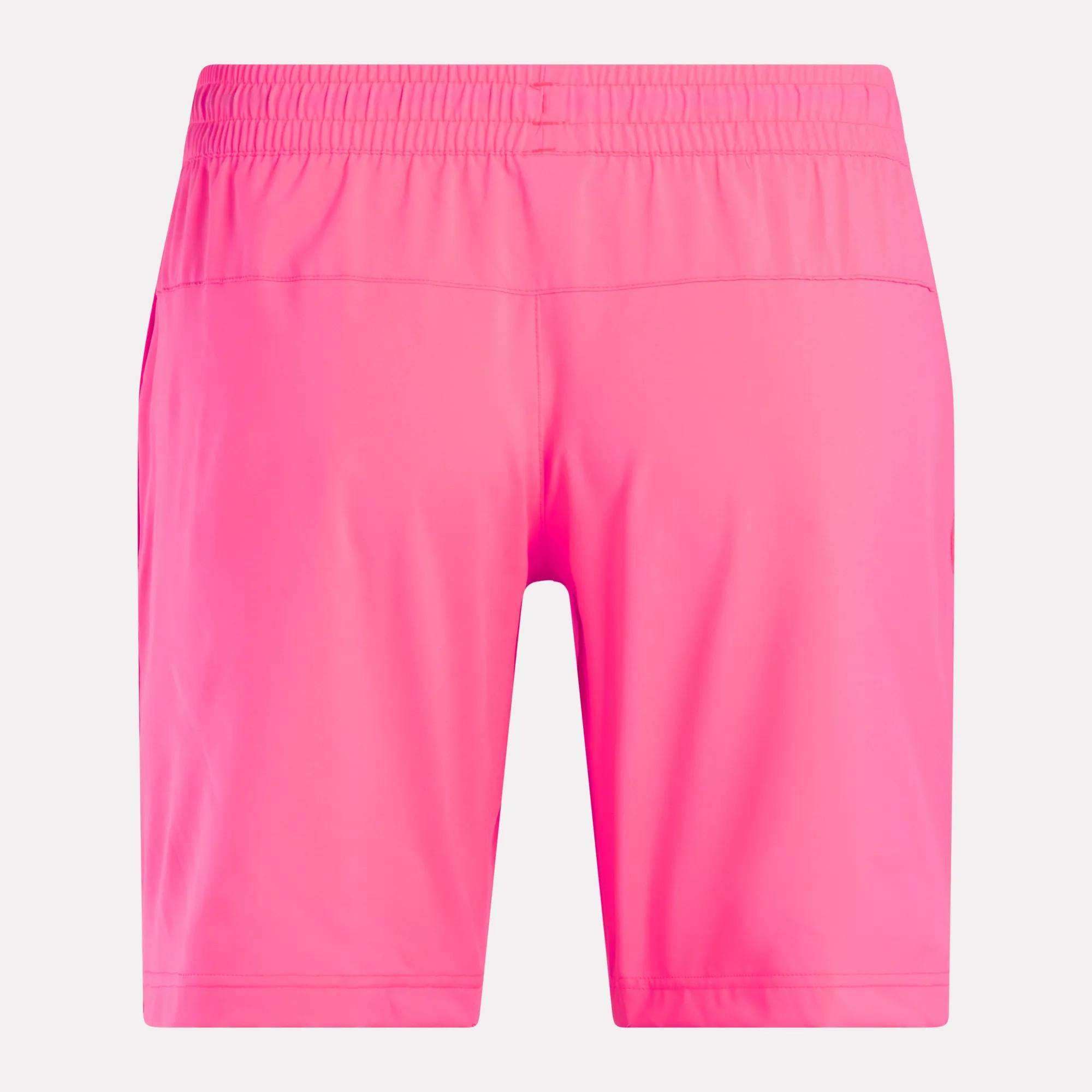 Men’s Workout Ready Woven Shorts by Reebok in bright pink, shown from the back. These shorts are knee-length with an elastic waistband and made from smooth, lightweight woven fabric, displayed against a plain white background.