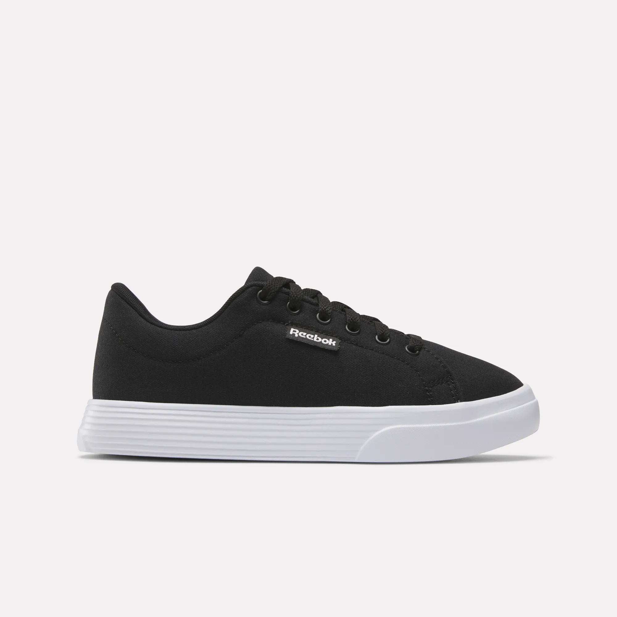 The Reebok Women's OnLux Court Lite Walking Shoes feature a black design with black laces and a white rubber sole, displayed in side profile on a light background—ideal for comfortable all-day walking.