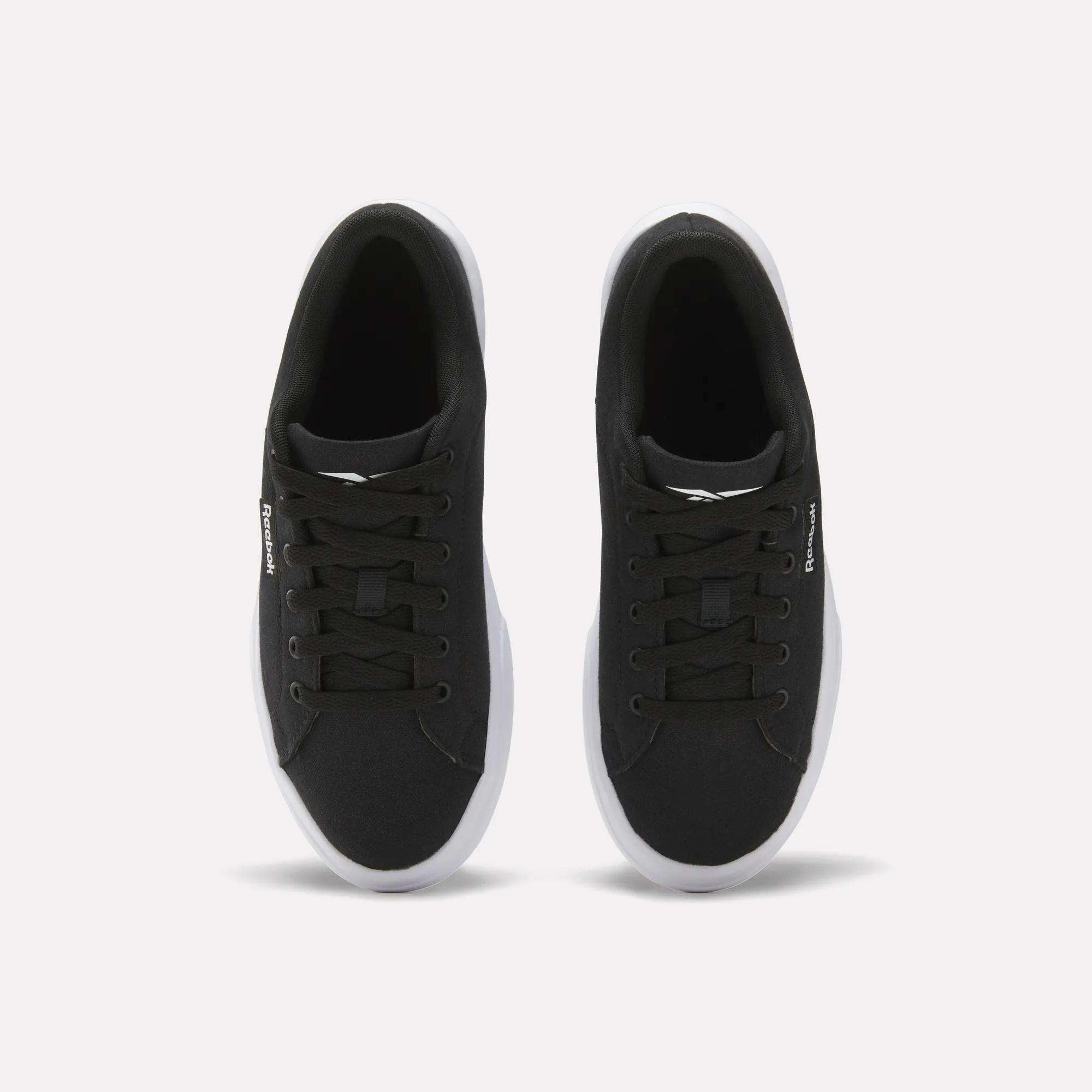 The Reebok Women's OnLux Court Lite Walking Shoes are black sneakers with white soles and black laces, shown from above on a plain white background. Their minimalist design makes them perfect for everyday wear.
