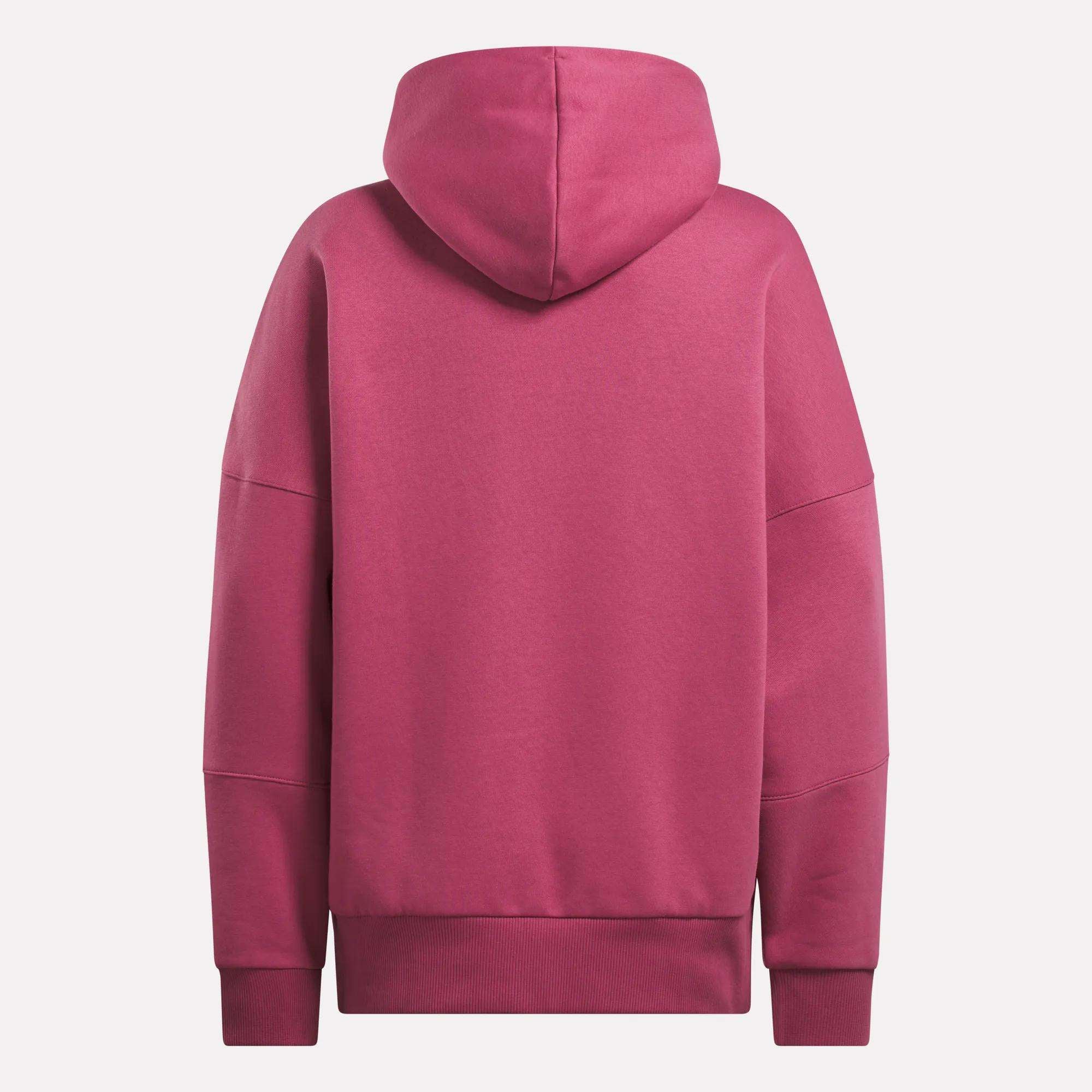 The Reebok Women's Lux Hoodie is shown from the back in magenta, featuring long sleeves, an oversized relaxed fit, ribbed cuffs and hem, and a hood, all displayed against a white background.