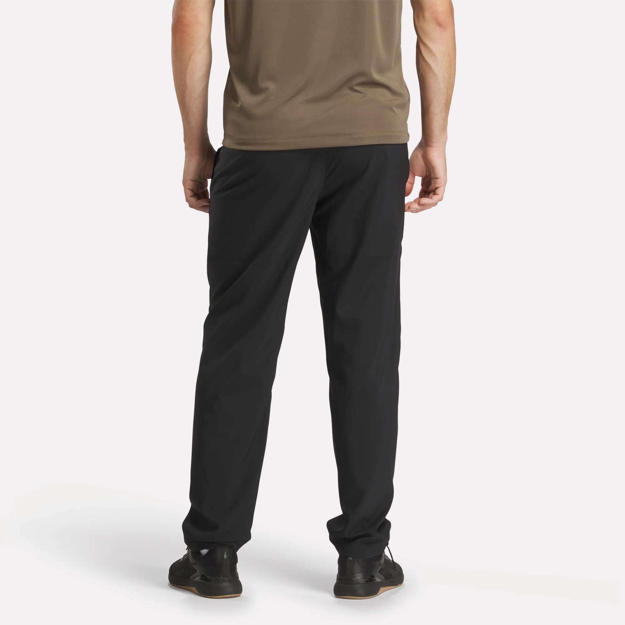 A man wearing Reebok Men's Train Woven Unlined Pants in black.