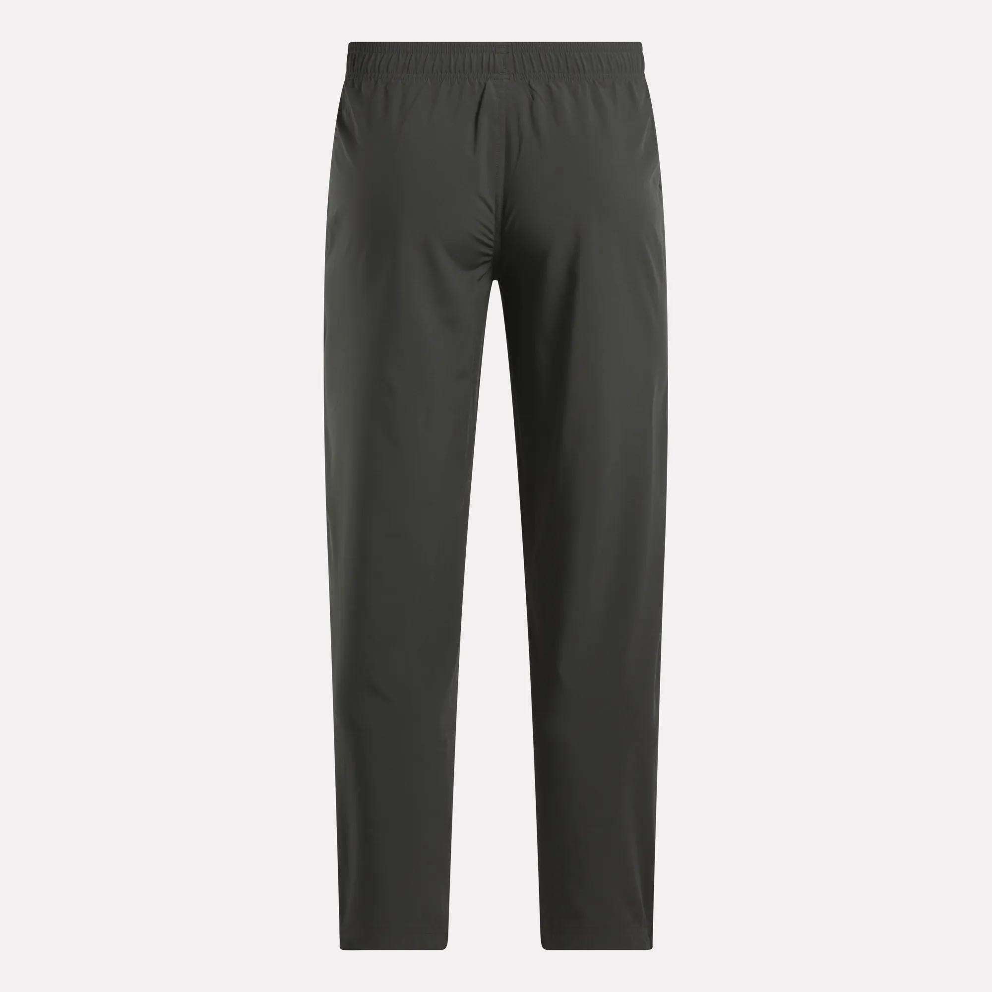Reebok Men's Train Woven Unlined Pants in dark gray feature a straight-leg design and elastic waistband, ideal as lightweight workout or gym pants. Shown against a light background.