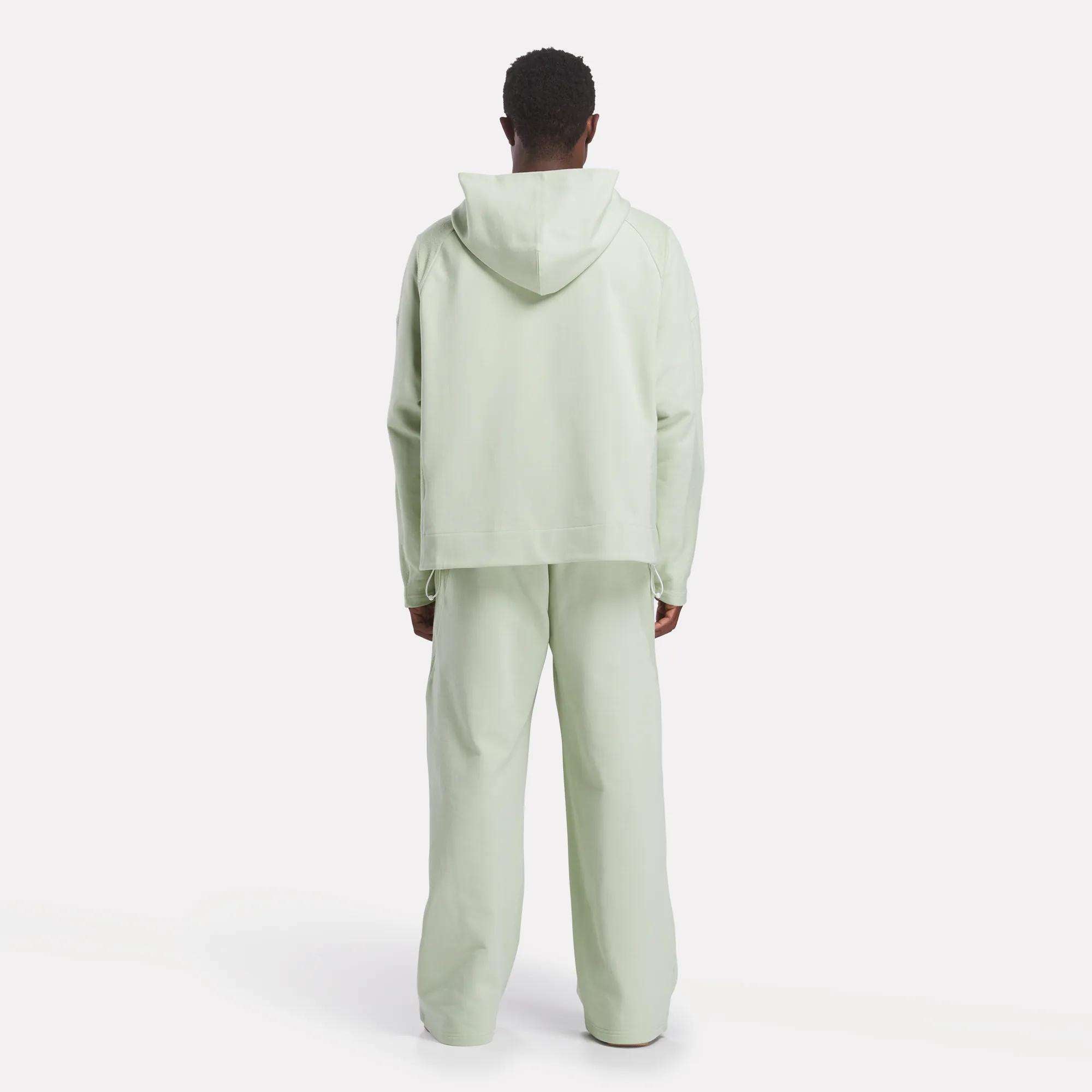 A person faces away from the camera, wearing a loose Reebok x CHUKWU Full-Zip Hoodie and matching French terry pants, set against a plain white background.