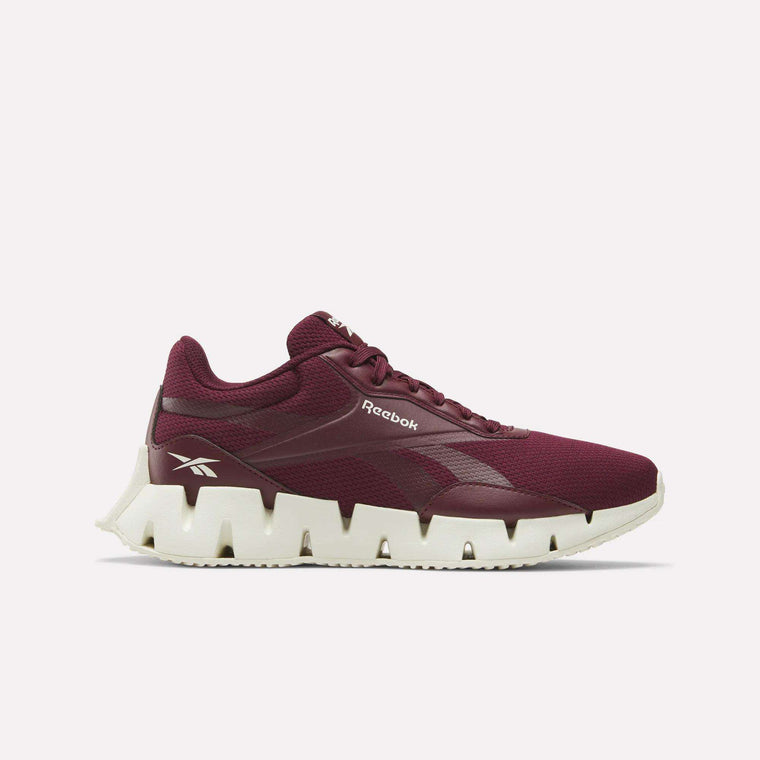 The Reebok Women's Zig Dynamica STR Shoes in maroon feature a breathable mesh upper, lace-up design, and white jagged sole for comfort and style, shown from the side against a plain white background.