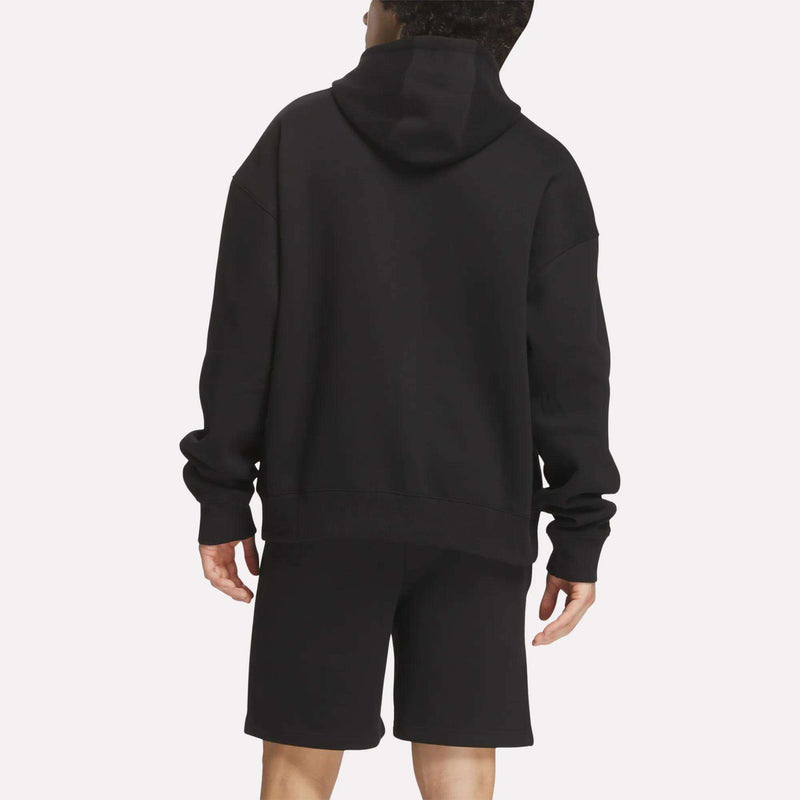 A person faces away from the camera, wearing a Reebok Men's Crest Hoodie with black shorts against a plain white background.