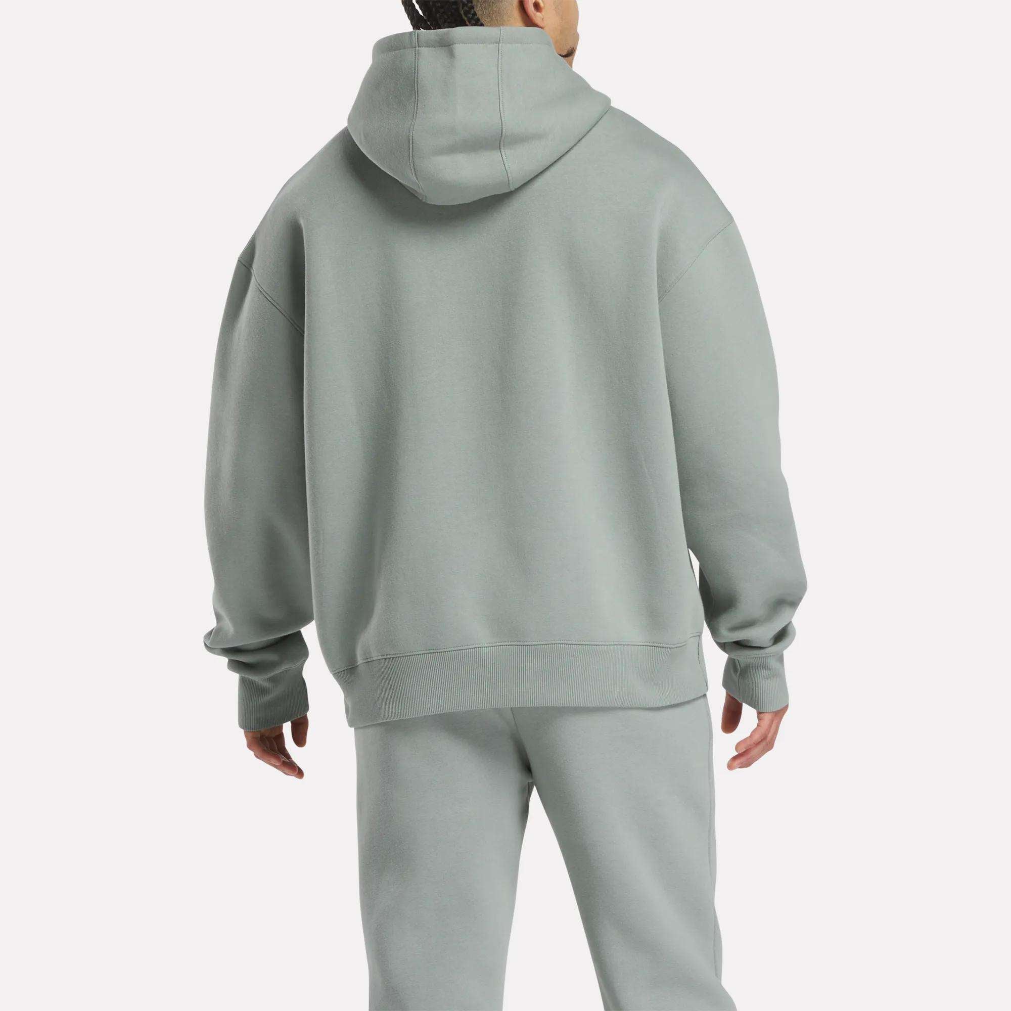 A person is shown from the back in a relaxed fit, light gray Men's Crest Hoodie and matching Reebok sweatpants made of soft fleece, set against a plain white background.