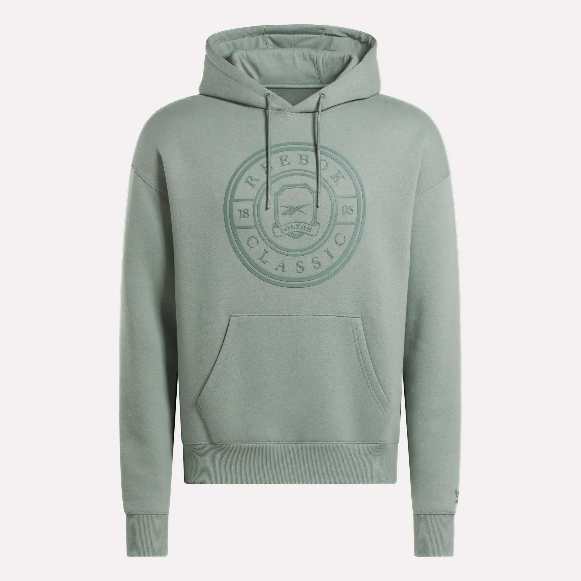 The Men's Crest Hoodie by Reebok is a light green soft fleece hoodie with a relaxed fit, front pocket, drawstring hood, and an embossed circular chest logo reading "Reebok Classic 1895 Bolton." Finished with long sleeves.