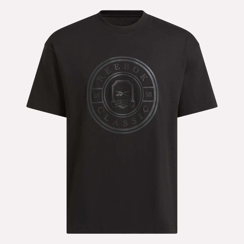 The Men's Crest T-Shirt by Reebok is a black cotton tee with a large dark circular emblem displaying REEBOK CLASSIC, BOLTON, and 1895—designed for everyday comfort.