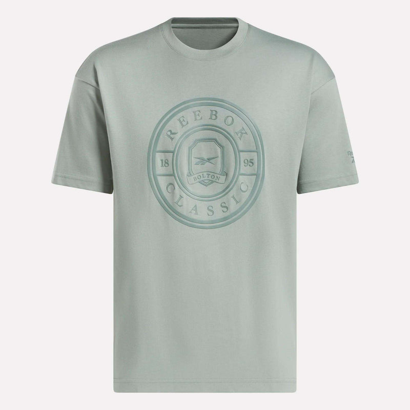 The Reebok Men's Crest T-Shirt is a light gray cotton tee with short sleeves and a crew neck, featuring a large circular Reebok Classic logo and Bolton 1895 text on the chest for everyday comfort.