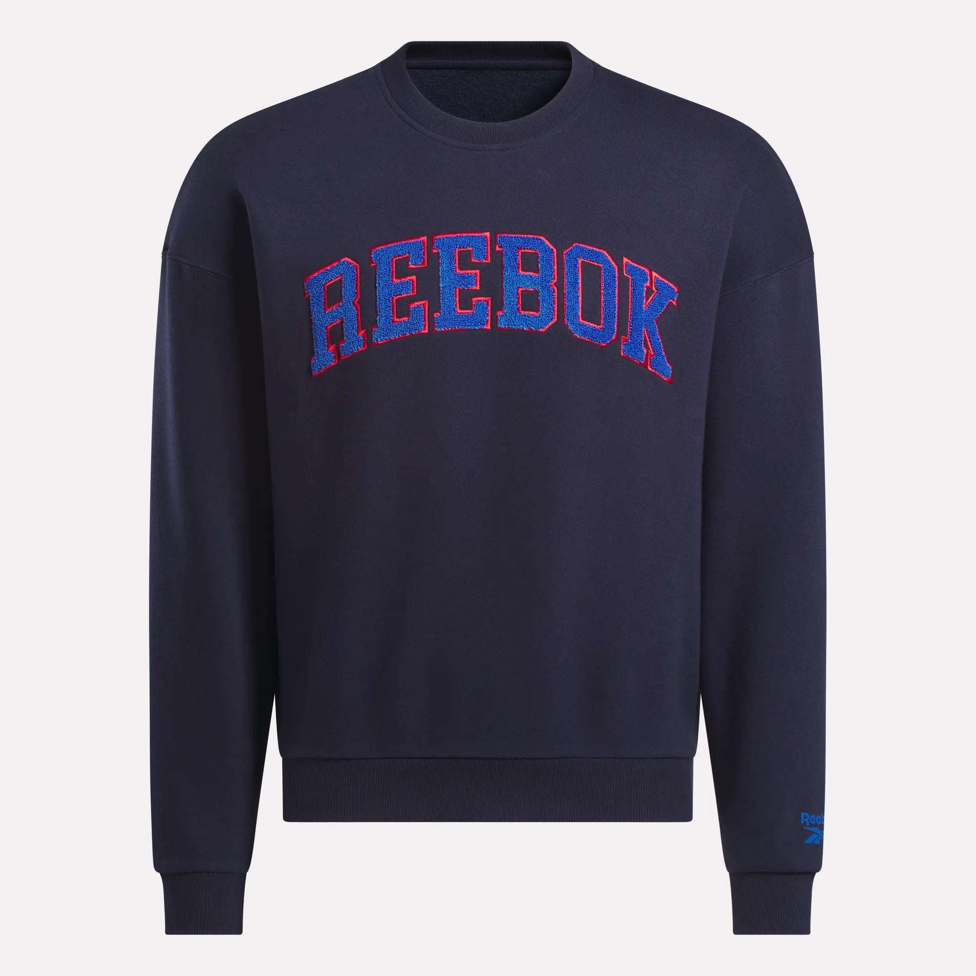 The Reebok Men's Crew Sweatshirt in navy features bold REEBOK lettering in red and blue outline across the chest, shown on a plain background.