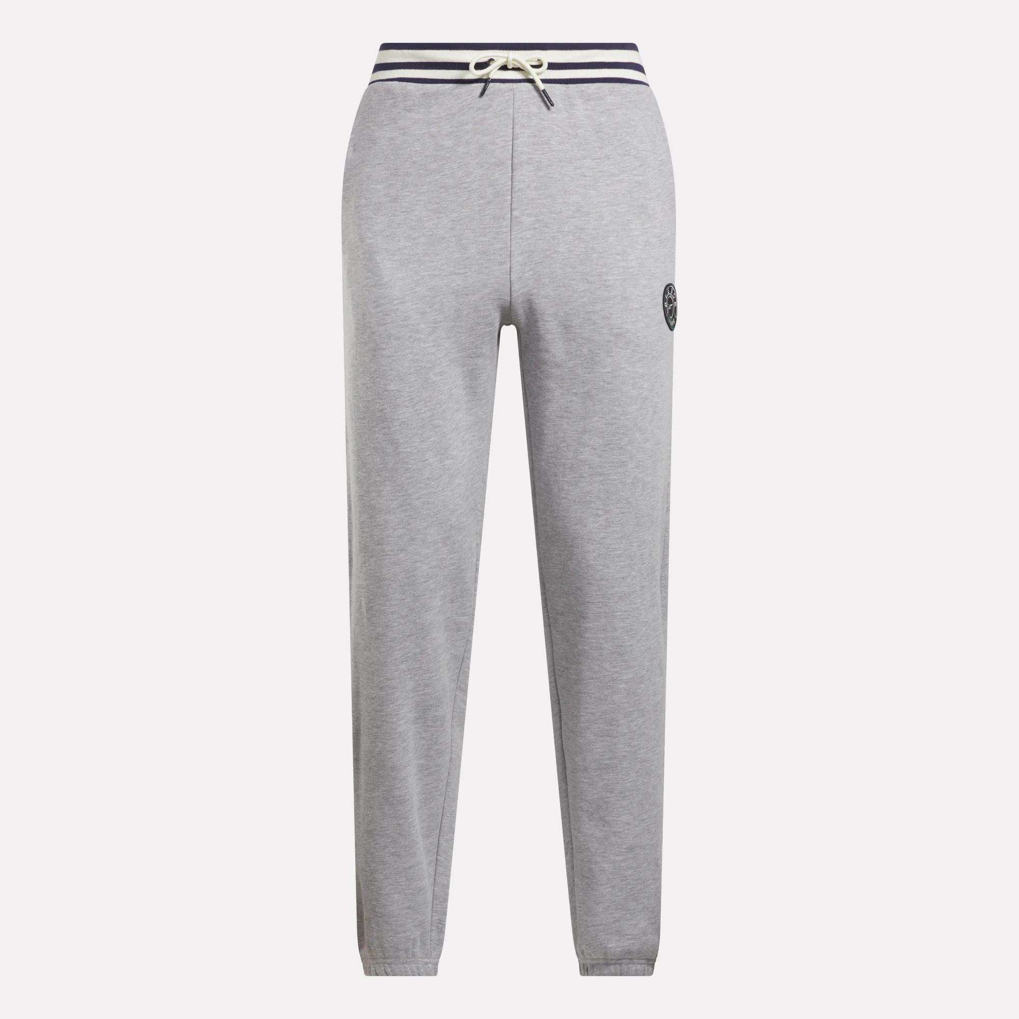 Reebok Men's Lawn Club French Terry Jogger Pants in light gray feature a cotton-blend fabric, navy striped drawstring waistband, straight legs, and a small circular logo on the left thigh. Stylish everyday sporty comfort. Shown on a white background.