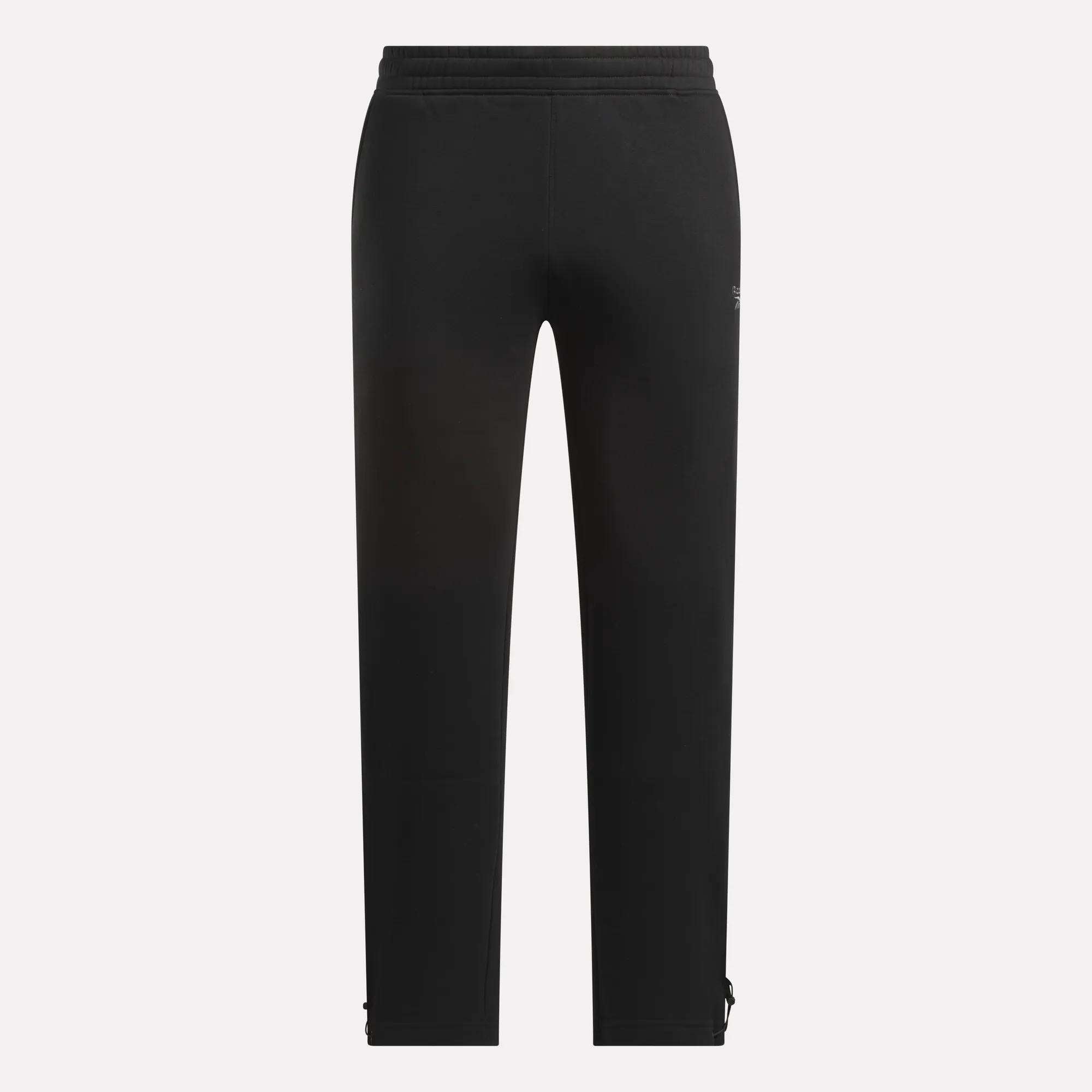 Seen from the back, these black Men's Wardrobe Essentials Pants by Reebok feature a straight leg with subtle seams and ankle zippers, crafted from soft cotton-blend fleece for comfort and finished with an elasticated waistband.