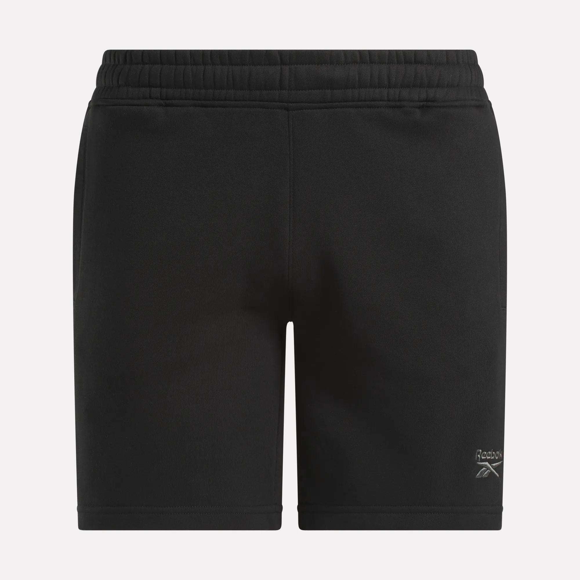 Men's Wardrobe Essentials Shorts by Reebok—black fleece shorts with an elastic waistband, white Reebok logo on the lower left leg, and a relaxed fit, shown against a plain white background.