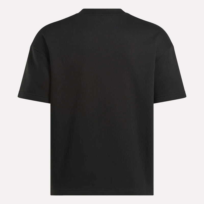 The image displays the back of a Men's Wardrobe Essentials T-Shirt by Reebok—a plain black, relaxed fit men's crewneck with no visible logos, patterns, or designs—set against a light background.