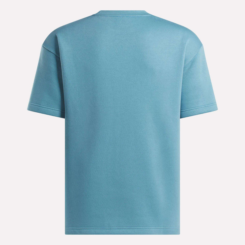 The Reebok Men's Wardrobe Essentials T-Shirt in classic blue is shown from the back against a white background, featuring short sleeves and a relaxed fit.