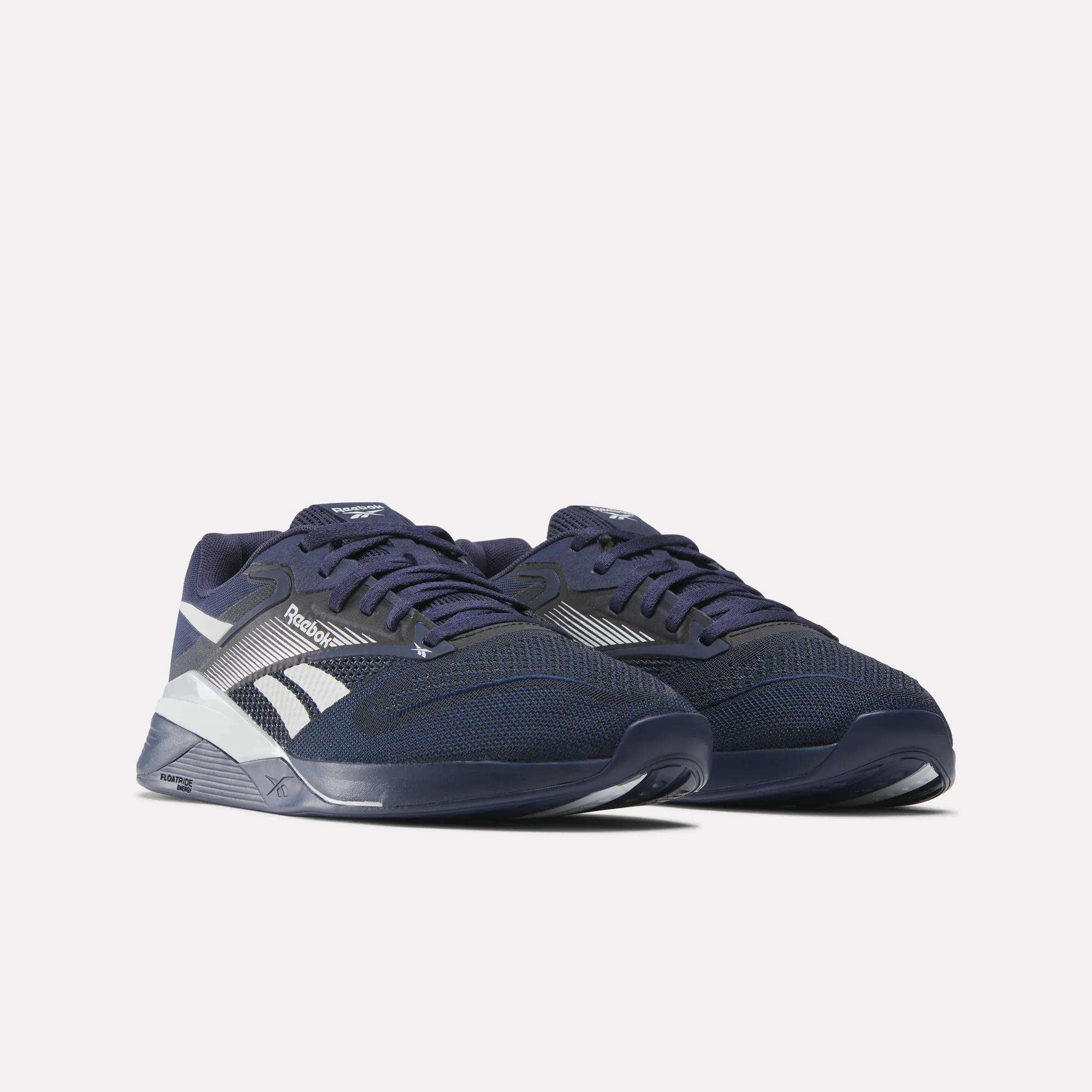 A pair of Reebok Nano X4 Training Shoes in navy blue with white accents and Flexweave mesh, showcased on a plain light background. Features include lace-up closure and cushioned soles for maximum comfort.
