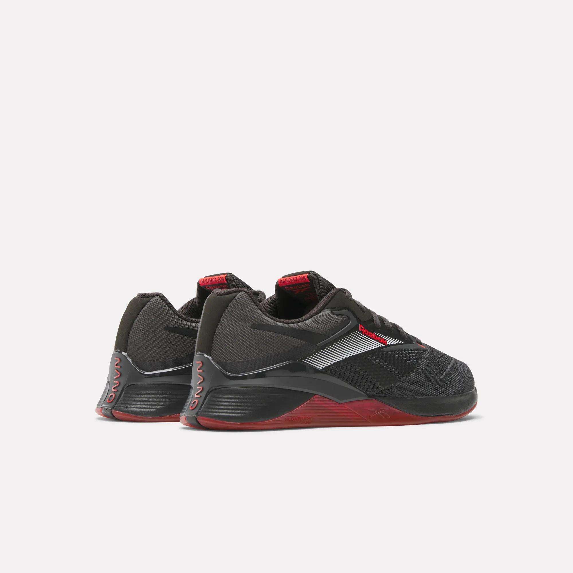 A pair of Reebok Nano X4 Training Shoes in black with red accents, mesh details, and textured soles are displayed side by side on a light background, slightly angled away from the viewer.