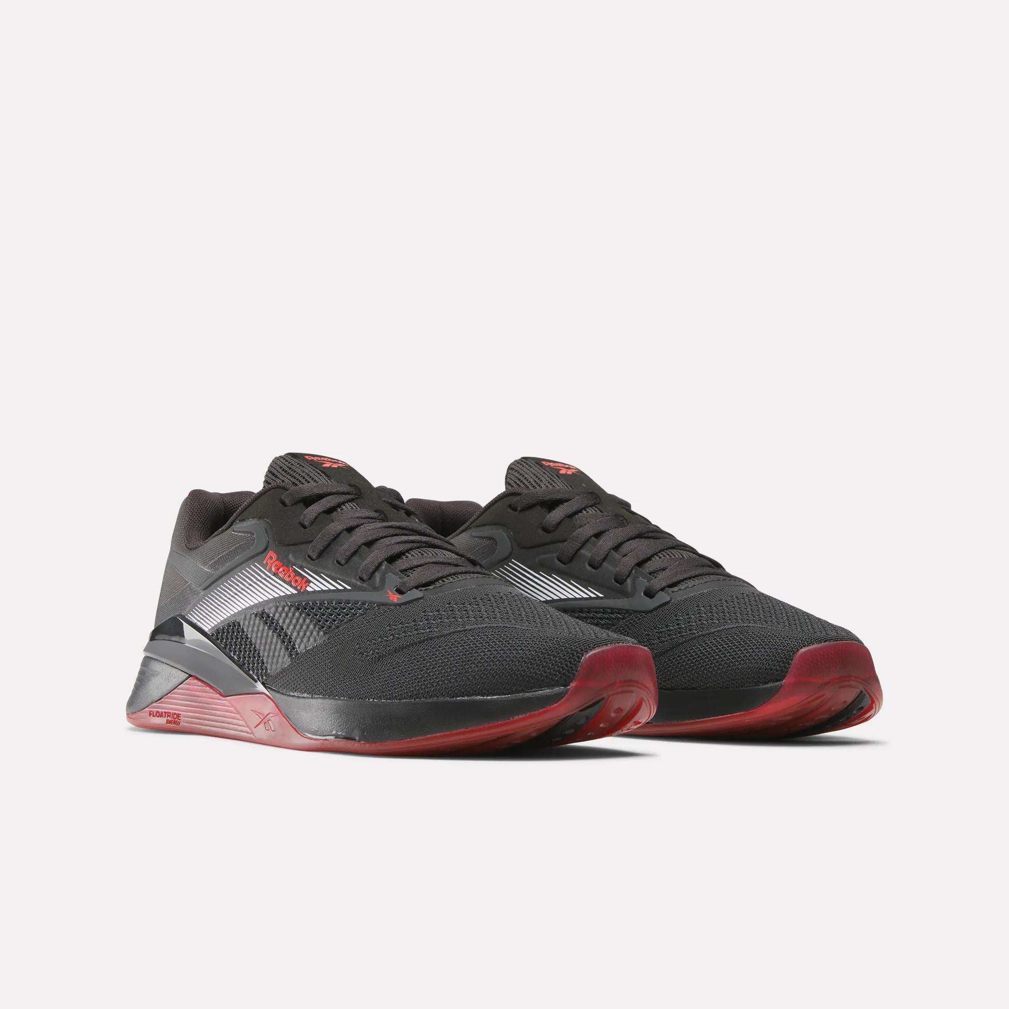 The Reebok Nano X4 Training Shoes are black with red accents and white side stripes, shown on a light background. These gym-ready sneakers have black laces and textured soles, ideal for athletic training.