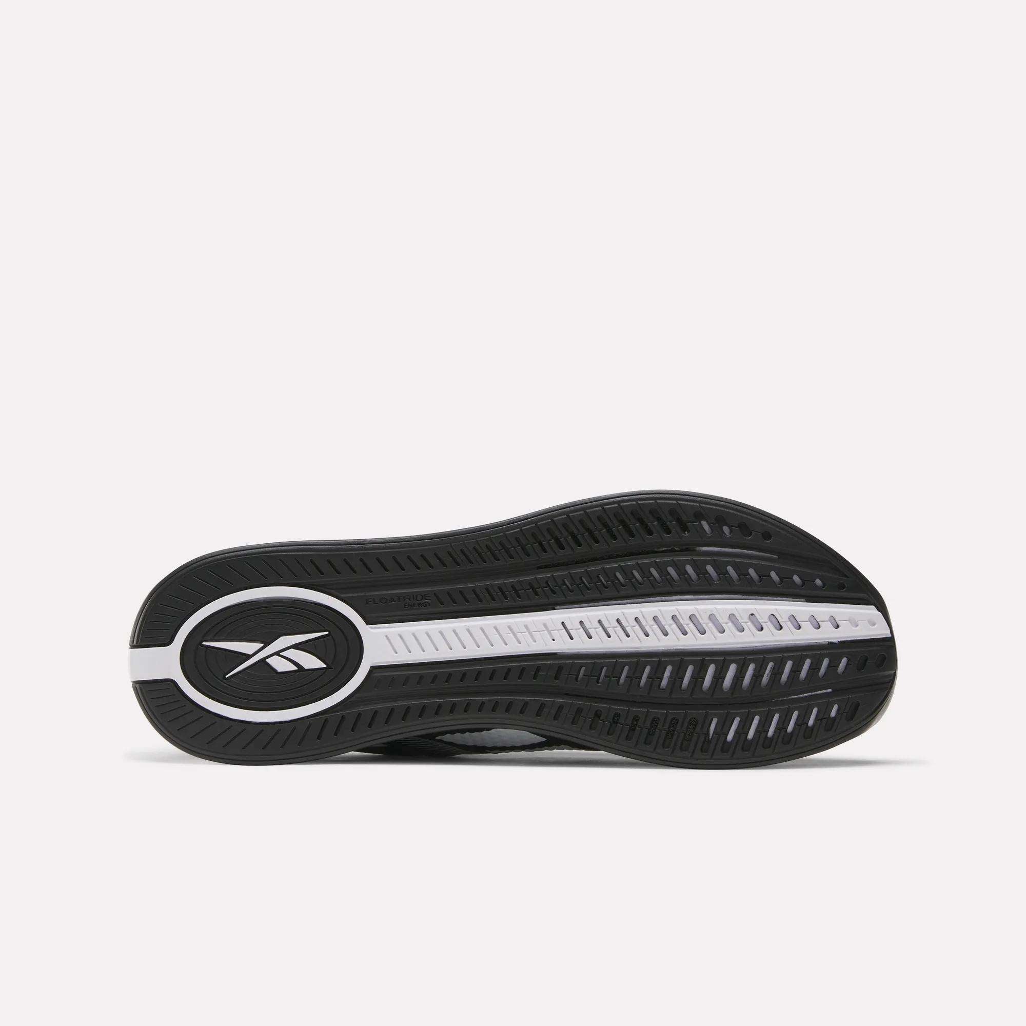 The image shows the black and white sole of Reebok Nano X4 Training Shoes, with the Reebok logo in an oval near the heel and a grooved pattern for traction.