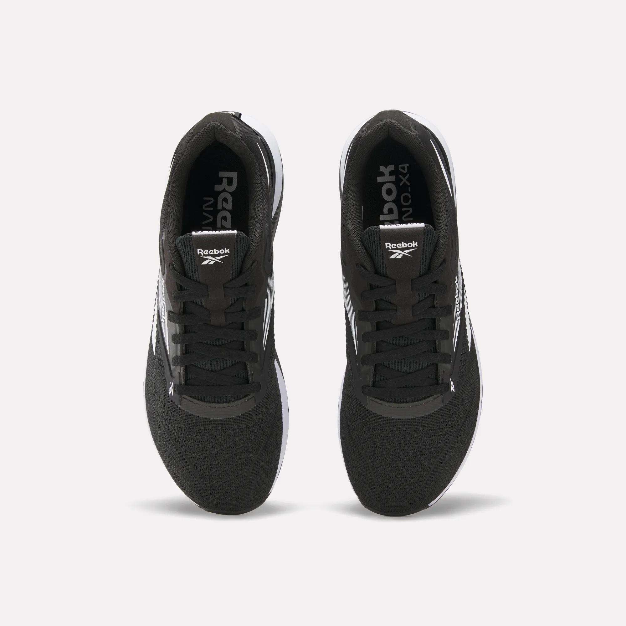Top view of a pair of black Reebok Nano X4 Training Shoes with white soles and visible Reebok logos on the tongue and inner sole, displayed side by side on a white background.