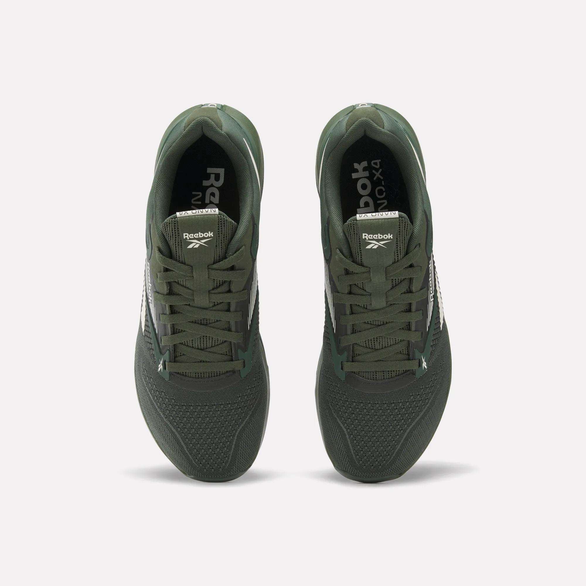 A pair of dark green Reebok Nano X4 Training Shoes viewed from above with laces, mesh toes, and the Reebok logo on the tongues and insoles, set against a white background. Features Floatride Energy Foam for comfort.