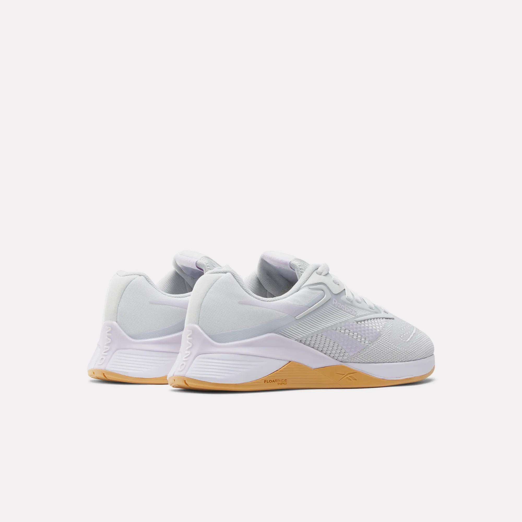 A pair of Reebok Women's Nano X4 Training Shoes in white with light brown rubber soles, breathable uppers, and supportive Floatride Energy Foam, shown from the side and slightly behind on a plain white background.